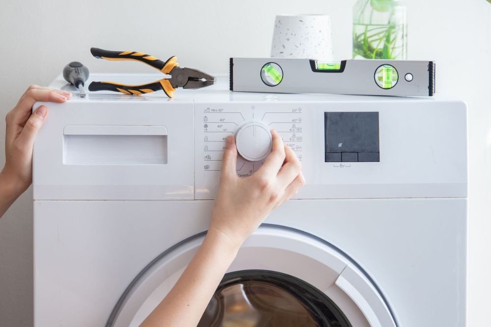 A woman adjusts a washing machine, illustrating a laundry appliance repair service based in Long Beach, California.