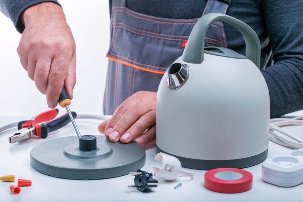 A man works diligently at a table with tools, providing small appliance repair services in Long Beach, CA.
